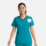 A teal women's top with a contrast double V-neck, featuring a logo and a name badge attachment.