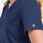A navy women's V-neck top with a chest pocket and a small logo on the sleeve.