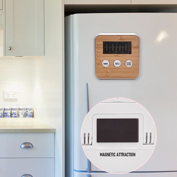 A multi-function electronic kitchen timer with a bamboo finish, displaying a digital countdown, mounted on a white fridge. A multi-function electronic kitchen timer with a bamboo finish, displaying a digital countdown, mounted on a white fridge.