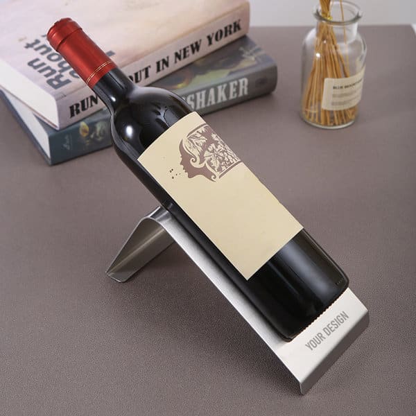 A drink bottle holder in stainless steel, angled to display a red wine bottle with a blank label, against a stylish background. A drink bottle holder in stainless steel, angled to display a red wine bottle with a blank label, against a stylish background.