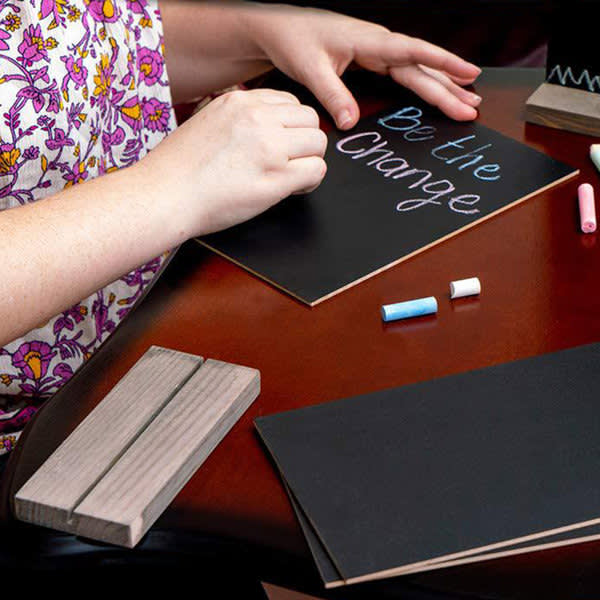 A set of tabletop chalkboard signs with a wooden base, accompanied by colourful chalk pieces, on a wooden table. A set of tabletop chalkboard signs with a wooden base, accompanied by colourful chalk pieces, on a wooden table.