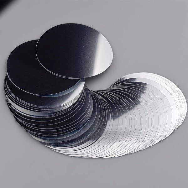 A collection of silver wine pourer discs arranged in a flowing pattern on a grey background, featuring a shiny finish. A collection of silver wine pourer discs arranged in a flowing pattern on a grey background, featuring a shiny finish.