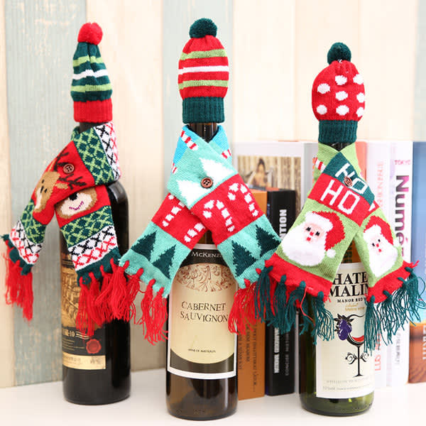 A drink bottle dressed in a red and green knitted hat and scarf, featuring festive patterns and colours. A drink bottle dressed in a red and green knitted hat and scarf, featuring festive patterns and colours.