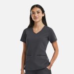 A women's V-neck top in dark grey with metallic details and front pockets, featuring a logo on the sleeve.