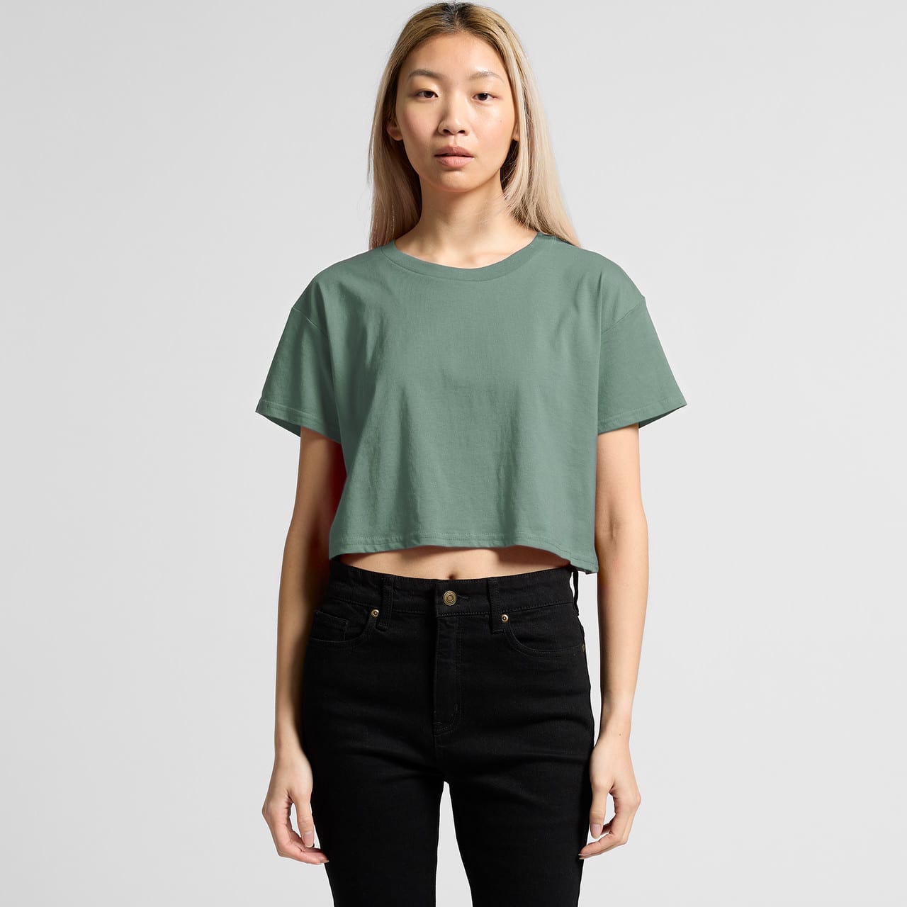 A cropped, green T-shirt with a relaxed fit, paired with black high-waisted jeans. The model stands in a neutral background. A cropped, green T-shirt with a relaxed fit, paired with black high-waisted jeans. The model stands in a neutral background.