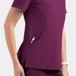 A women's contrast v-neck top in burgundy with a side pocket, featuring a subtle logo.