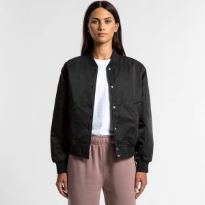 A black bomber jacket featuring a front snap closure, worn over a white shirt and light-coloured pants.