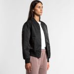A black varsity bomber jacket worn by a model, featuring a front snap closure and ribbed cuffs.