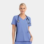 A mock wrap top in light blue with contrast navy panels and a pocket, featuring a stethoscope around the model's neck.