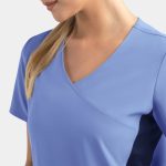 A women's mock wrap top in light blue with contrasting panels, featuring short sleeves and a v-neck design.