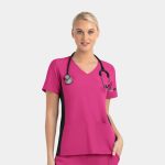 A woman wearing a pink mock wrap top with black contrast panels and a stethoscope around her neck.