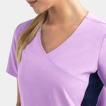 A lilac mock wrap top with contrast navy panels, featuring a v-neck design and short sleeves. It has a logo.