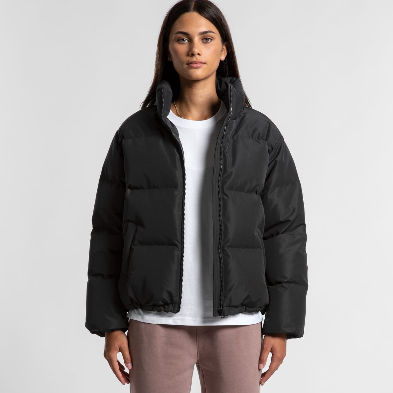 A puffer jacket in black, featuring a zip-up front and a casual, oversized fit. The model wears a white top underneath. A puffer jacket in black, featuring a zip-up front and a casual, oversized fit. The model wears a white top underneath.