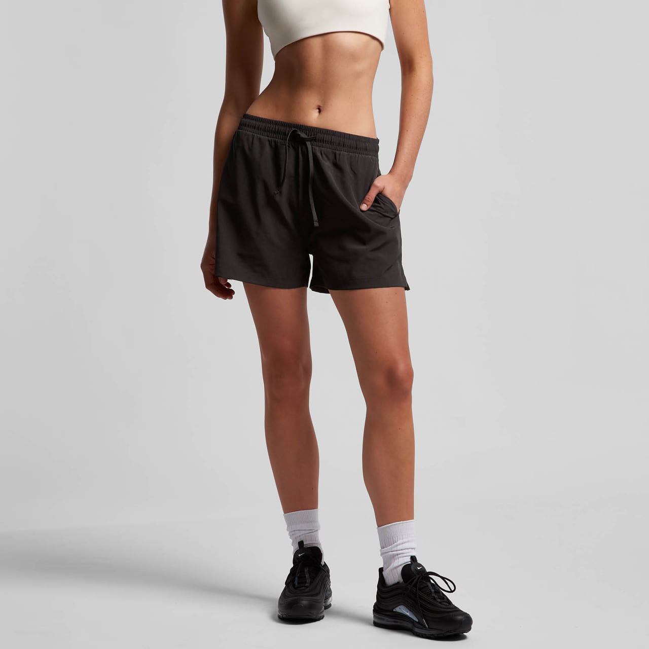 Active shorts in dark grey, featuring an elastic waistband, drawstring, and side pockets, worn with a cropped top. Active shorts in dark grey, featuring an elastic waistband, drawstring, and side pockets, worn with a cropped top.