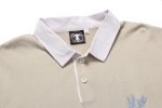 A beige sports jumper featuring a white collar and a logo. It has three buttons at the neck and embroidered detail.