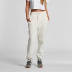 Track pants in cream, featuring a comfortable waistband and side pockets, paired with sporty footwear.