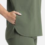 A green women's top featuring a dolman style and three pockets on the sides.