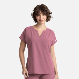 A woman in a short-sleeved, dusty pink top with a pocket, featuring a logo on the shoulder.