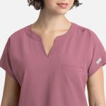 A close-up of a women's dolman top in mauve, featuring short sleeves and a single chest pocket. It has a logo.