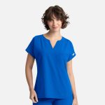 A woman wearing a bright blue dolman top featuring a v-neck and a single pocket. The top has rolled short sleeves.