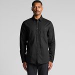 A black work shirt featuring long sleeves, a button-up front, and two chest pockets, with a logo.