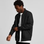 A black bomber jacket with a zip front and ribbed cuffs, worn by a person adjusting the sleeve.