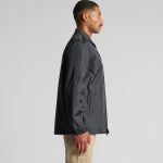 A black Coach Jacket is displayed on a model, featuring a simple design and a logo on the front.