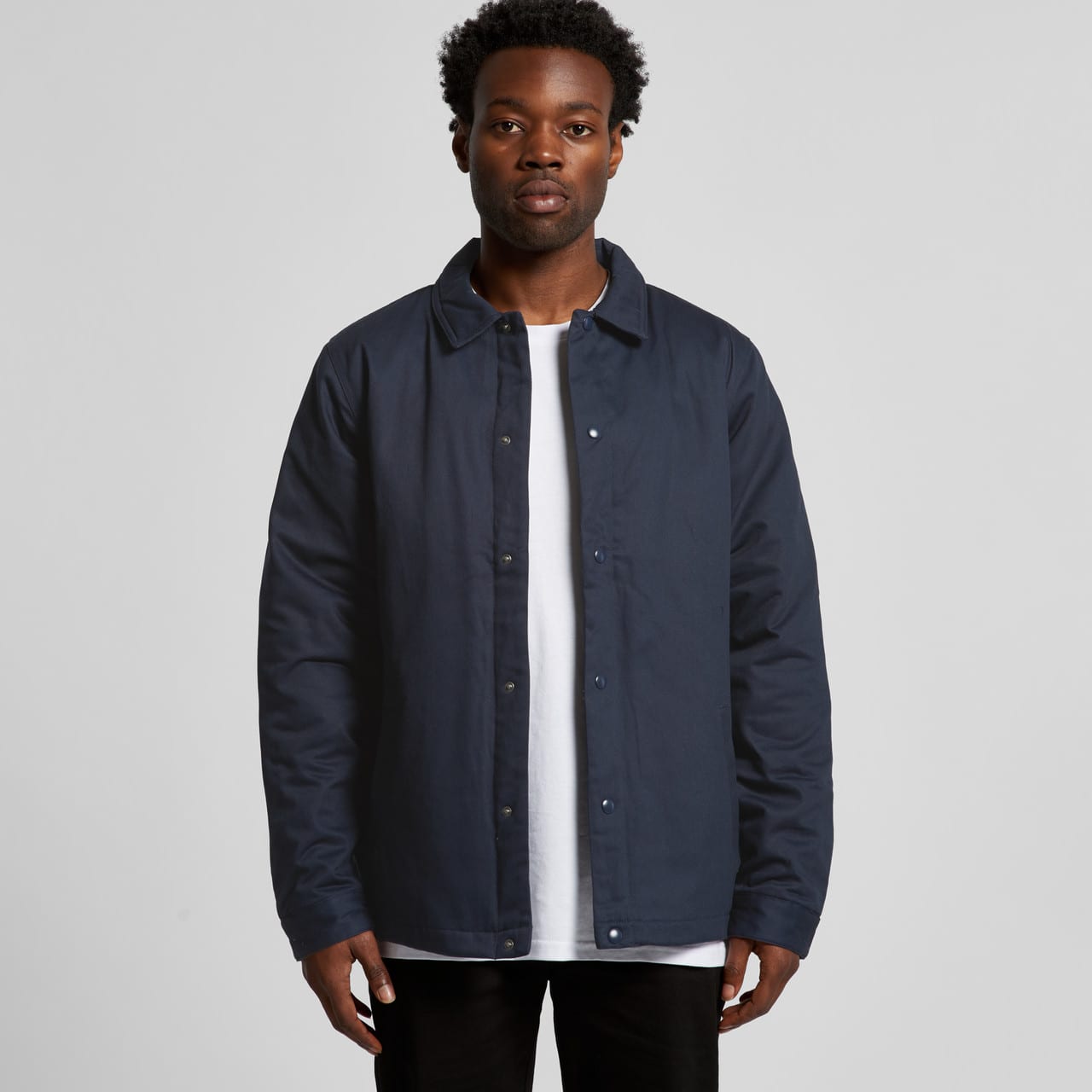 A dark navy work jacket with a button-up front and a classic collar on a model. Contains a logo on the chest. A dark navy work jacket with a button-up front and a classic collar on a model. Contains a logo on the chest.