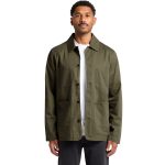 A man wearing an olive green Chore Jacket with multiple pockets and a logo. The jacket has a classic collar and button front.