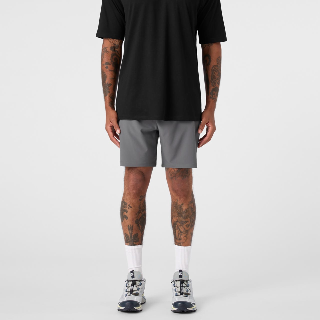 A pair of grey sports shorts paired with a black top, worn by a person with visible tattoos. A pair of grey sports shorts paired with a black top, worn by a person with visible tattoos.
