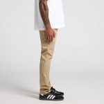 A pair of khaki standard pants displayed on a model, paired with black shoes and a white shirt.