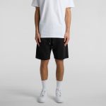 A person wearing black sports shorts styled with a plain white t-shirt and white sneakers.