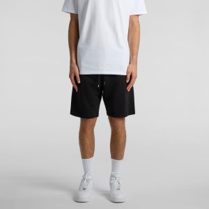 A person wearing black sports shorts styled with a plain white t-shirt and white sneakers.