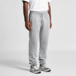 Grey track pants displayed on a person, featuring an elastic waistband and cuffs, with a logo present.