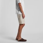 Linen shorts in a light beige colour, featuring a relaxed fit, paired with a white t-shirt and brown footwear.