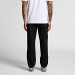 Relaxed pants in black featuring a relaxed fit, viewed from the back. The model wears a white shirt and sneakers.