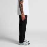 Black relaxed pants showcased on a model, paired with a white t-shirt and grey sneakers. The model stands sideways.