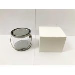 A medium clear PVC bucket with a metal handle next to a plain white box.