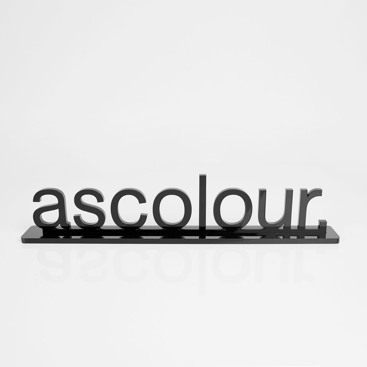 A black promotional product featuring the word "ascolour" in bold lettering on a sleek base. A black promotional product featuring the word "ascolour" in bold lettering on a sleek base.
