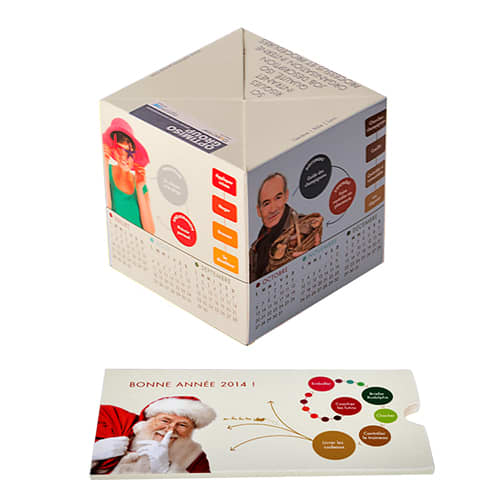 A paper pop-up cube in cream colour featuring various images and a calendar layout, presented with a flat card. Paper Pop Up Cube - Image 1