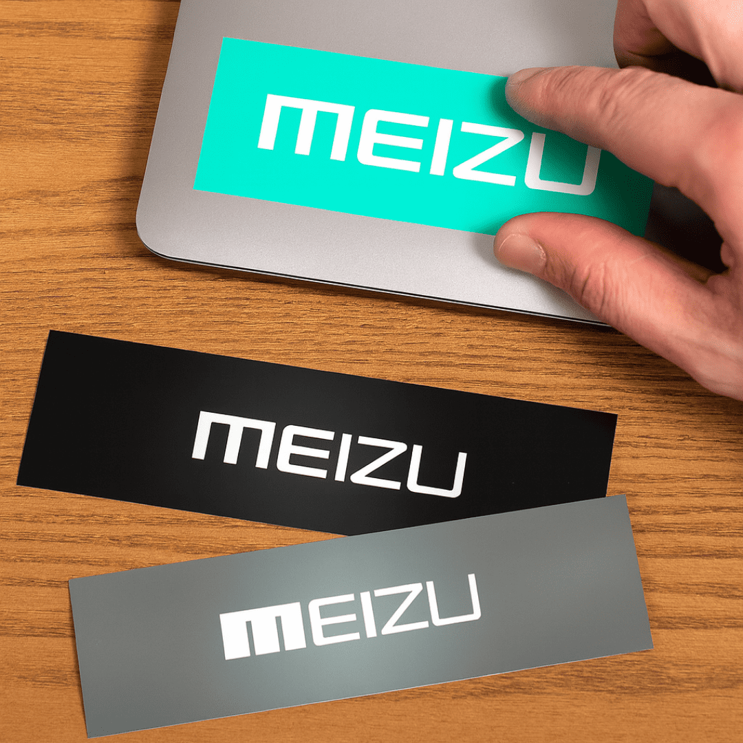 Three rectangular gloss paper stickers in turquoise, black, and grey, with a logo on each, placed on a wooden surface. Gloss Paper Sticker (75 x 210mm) - Image 1