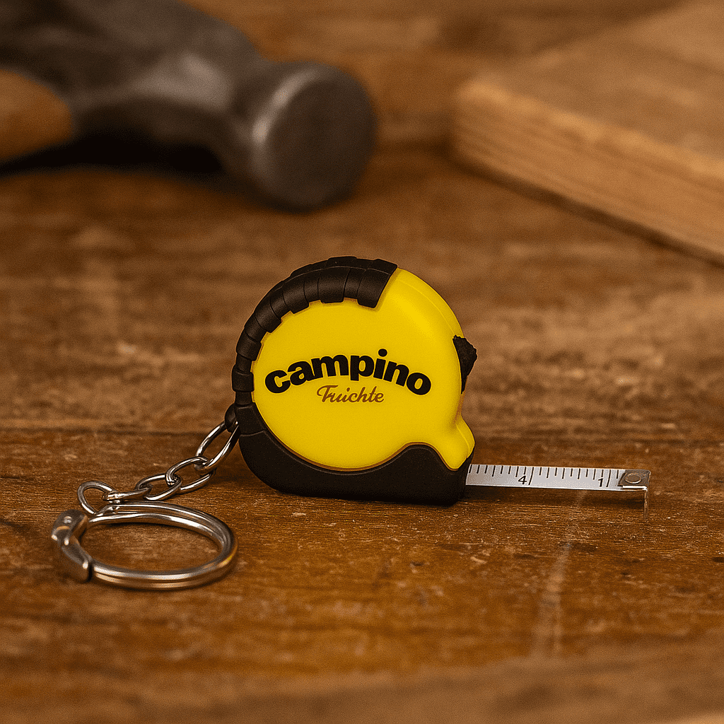 A mini tape measure in yellow and black with a keychain attachment, resting on a wooden surface. Mini Tape Measure - Image 1