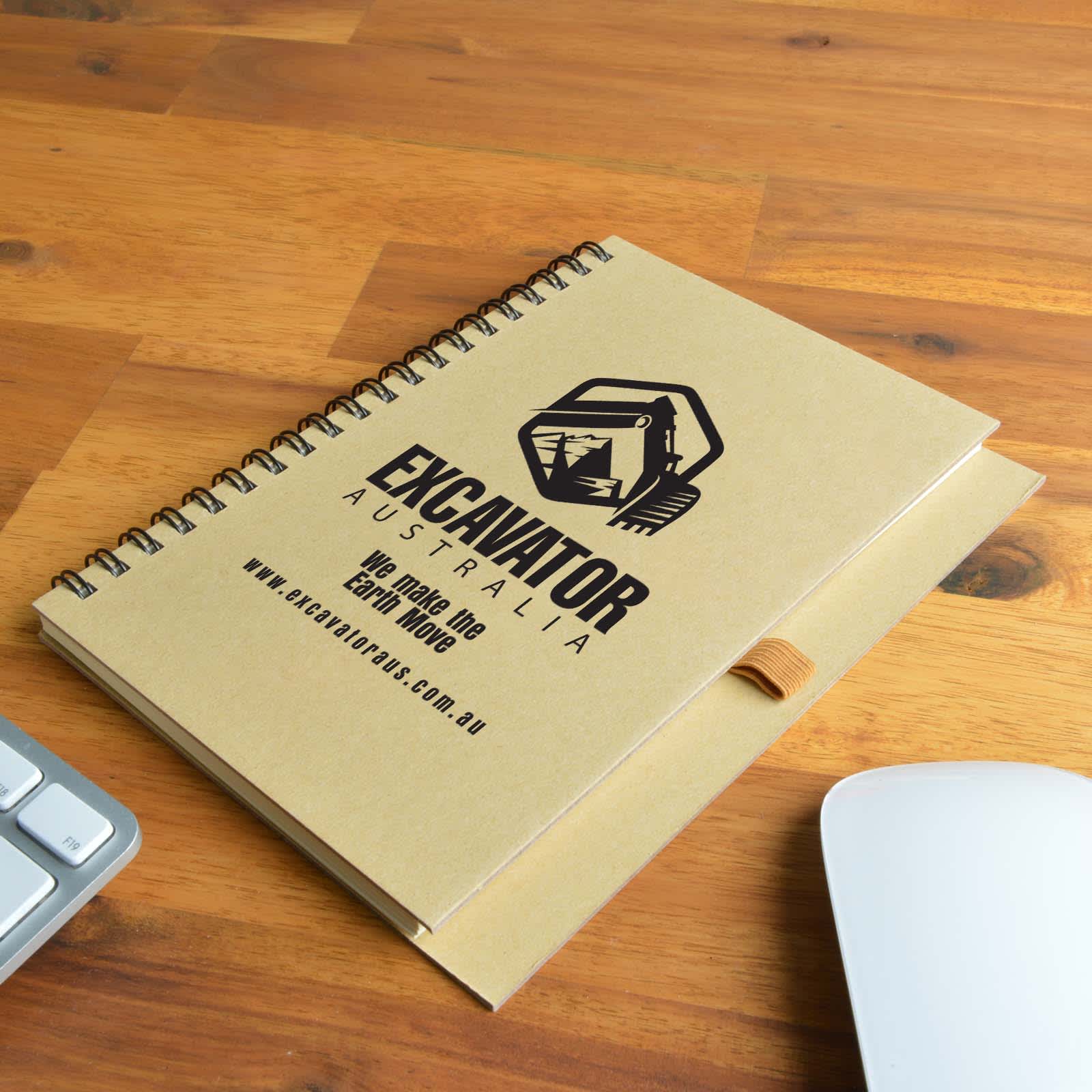 A brown spiral-bound notebook with an elastic strap, featuring a logo and branding on the cover. Savannah Notebook - Image 1