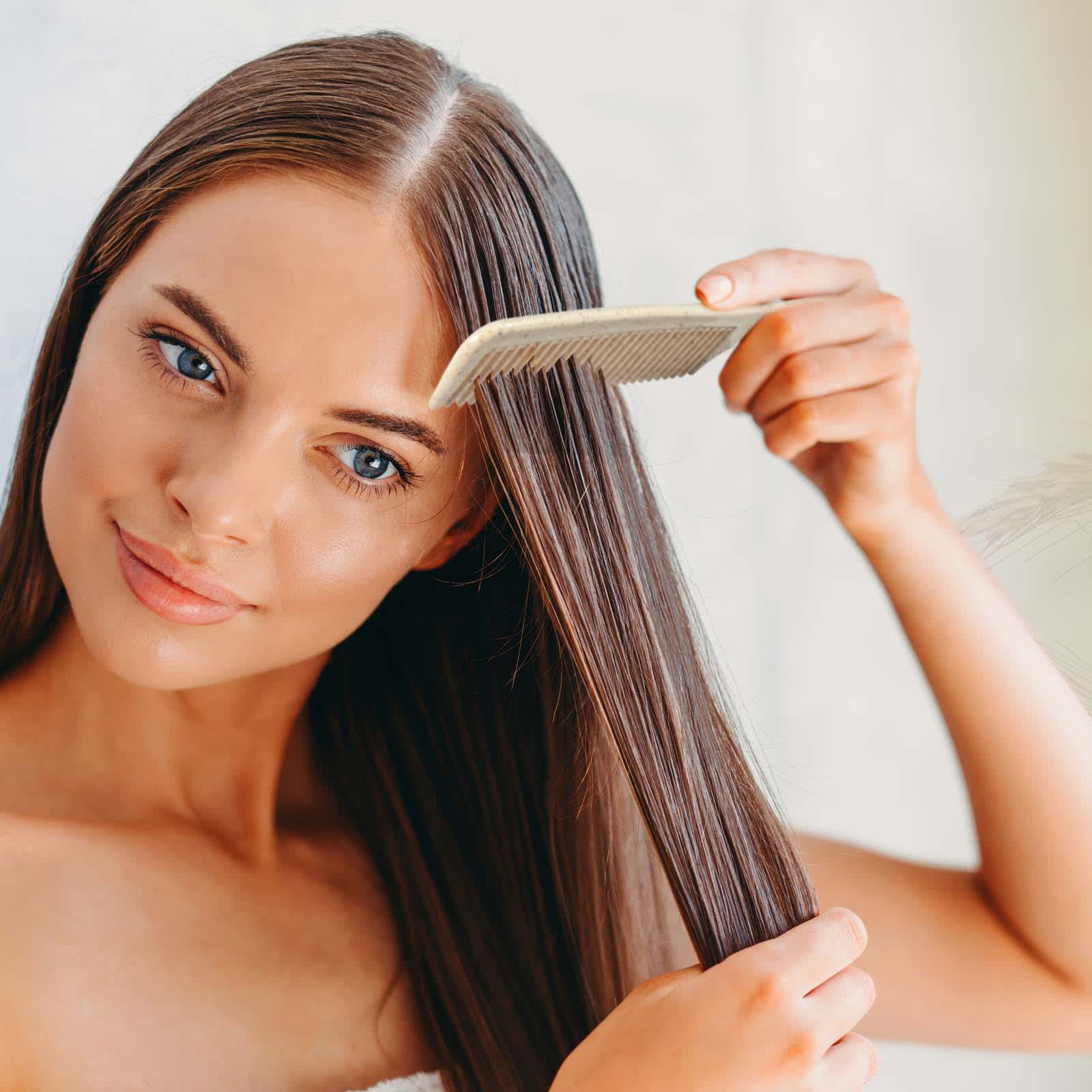 A woman is using a Lynx Wheat Fibre Comb to style her long, straight hair. Lynx Wheat Fibre Comb - Image 1