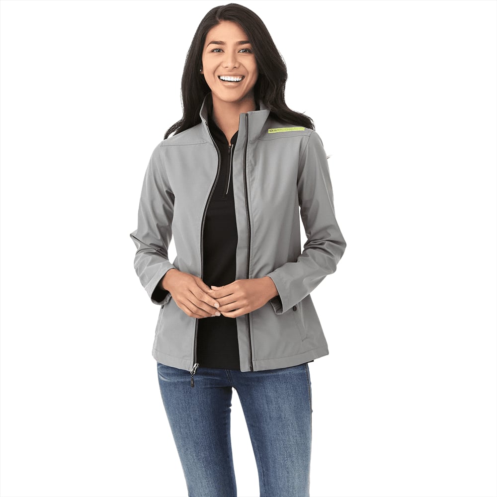 A grey women's softshell jacket with a fitted style, featuring a zip front and a logo on the upper arm. Karmine Softshell Jacket - Womens - Image 1