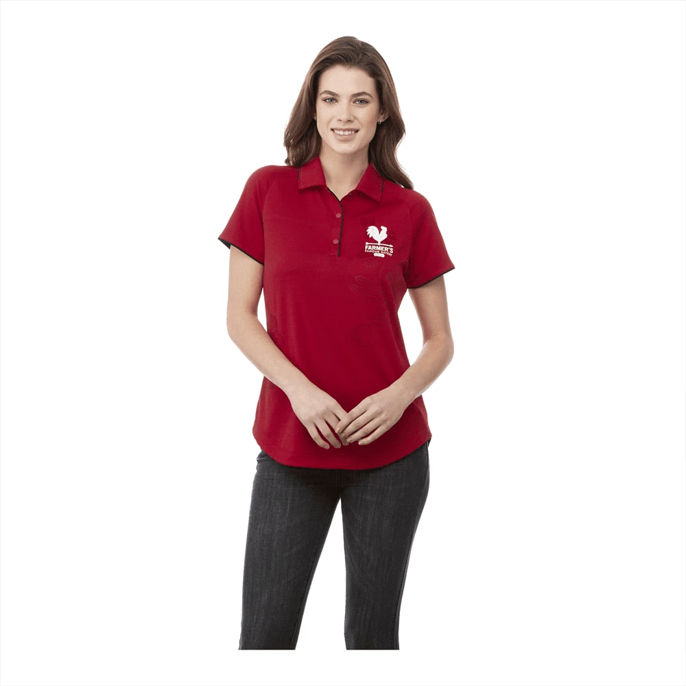 A women's short sleeve polo shirt in red, featuring a logo. The model is wearing it with dark jeans. Remus Short Sleeve Polo - Womens - Image 1