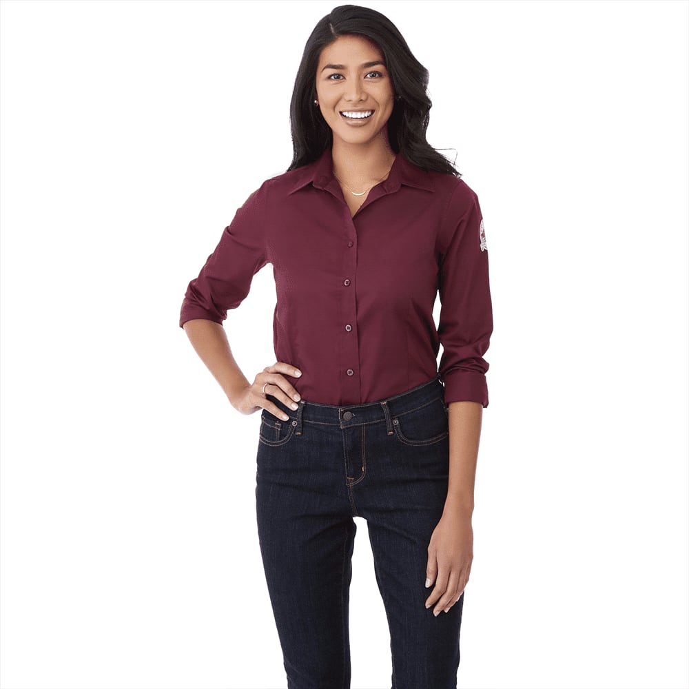 A burgundy long sleeve button-up shirt for women, featuring a logo on the sleeve, paired with dark jeans. Wilshire Long Sleeve Shirt - Womens - Image 1