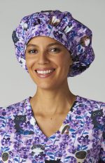 A bouffant cap featuring a purple floral print, worn by a smiling woman in a matching scrub top.