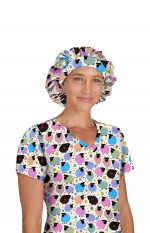 A bouffant cap featuring a colourful pattern of sheep on a light background, worn by a person in a matching top.