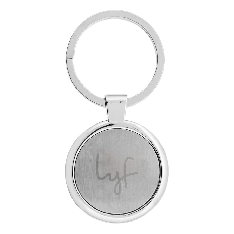 A silver keychain with a circular design featuring a branding logo on one side. Anello Keychain - Image 1
